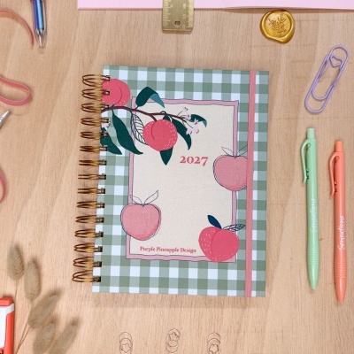 Agenda 2027 com capa quadriculada verde e branco decorada com pêssegos e maçãs cor-de-rosa