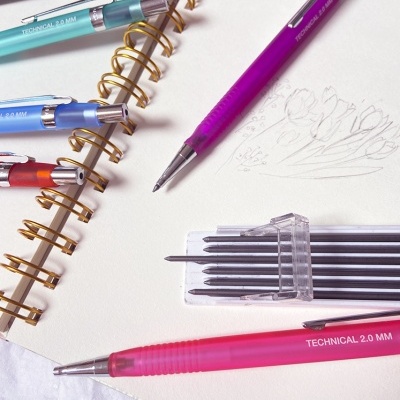 Canetas técnicas coloridas e estojo de recargas sobre caderno espiral de desenho