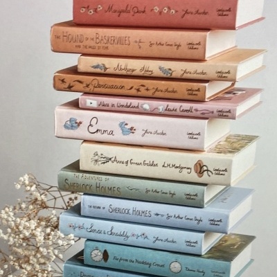 Pilha de livros clássicos com capas duras coloridas e textos manuscritos