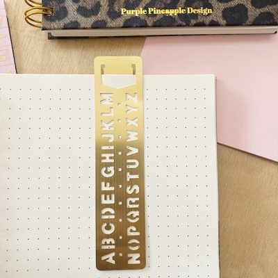 Marcador de livro dourado com letras do alfabeto e agenda com padrão animal print
