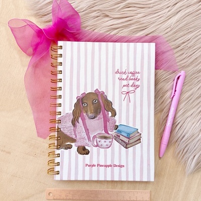 Caderno decorado com cão e livros, caneta rosa e régua