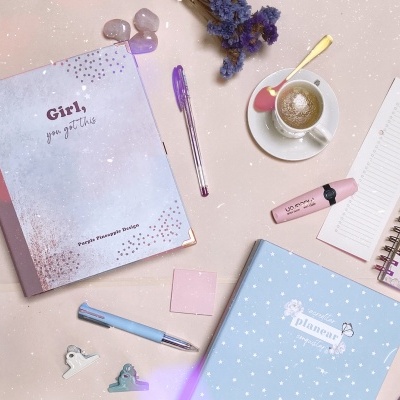 Mesa com cadernos, canetas, marcador, café e acessórios de escrita