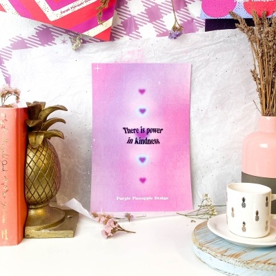 Cartaz motivacional rosa lilás com frase sobre bondade em ambiente decorativo