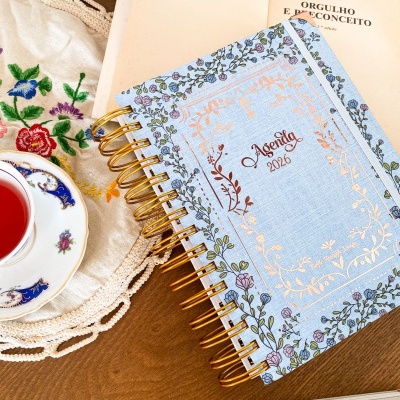 Agendas 2026 com capa azul clara e padrão floral com espiral dourada