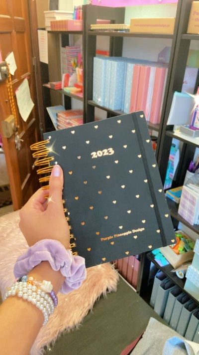 Agenda preta 2023 com corações dourados e espiral dourada