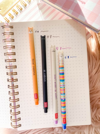 Quatro canetas coloridas com tampa de orelhas de animal em papel de caderno pontilhado