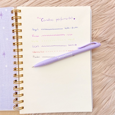 Caderno com escrita colorida e caneta roxa Sensations sobre superfície felpuda