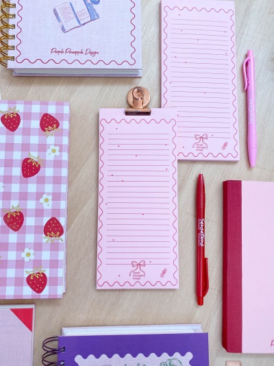 Artigos de papelaria rosa, blocos de notas, cadernos com padrão de morangos e canetas