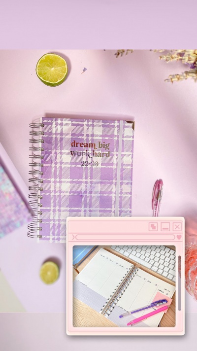 Caderno espiral lilás com texto e caneta rosa sobre superfície cor de rosa