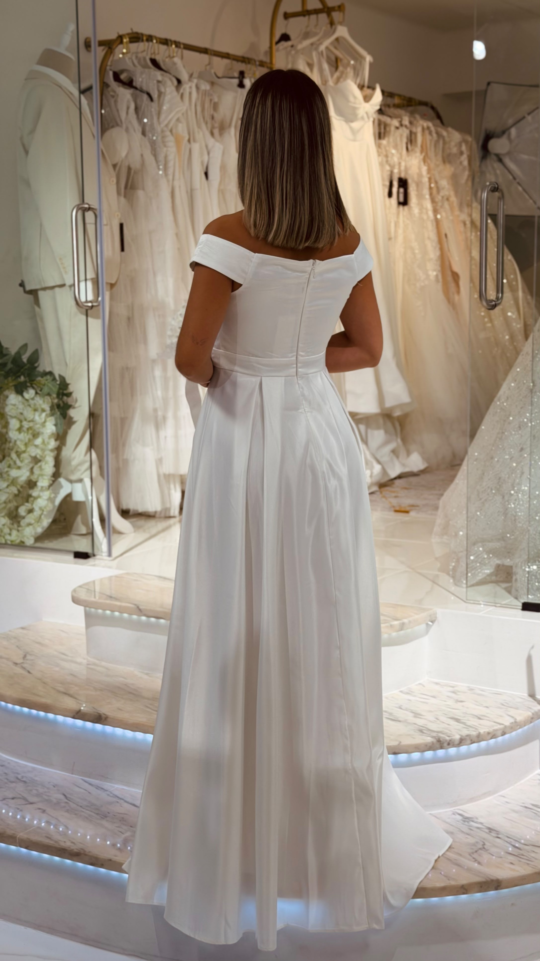 Vestido Santa Noiva Vestido branco de noiva acetinado com corte ombro a ombro em loja de noivas