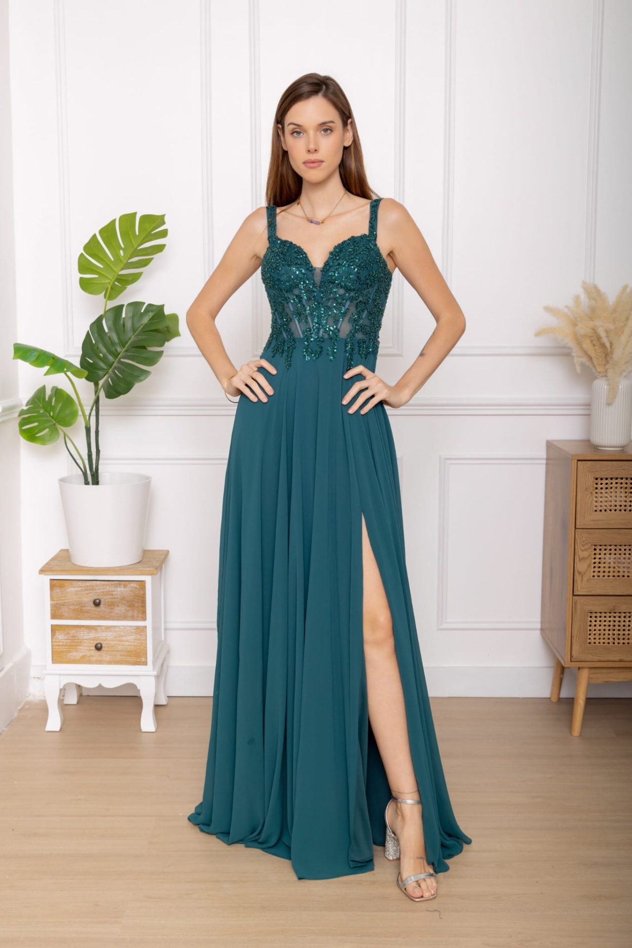 Vestido Brasil Vestido verde-azulado bordado com fenda lateral e sandálias prateadas num ambiente interior minimalista