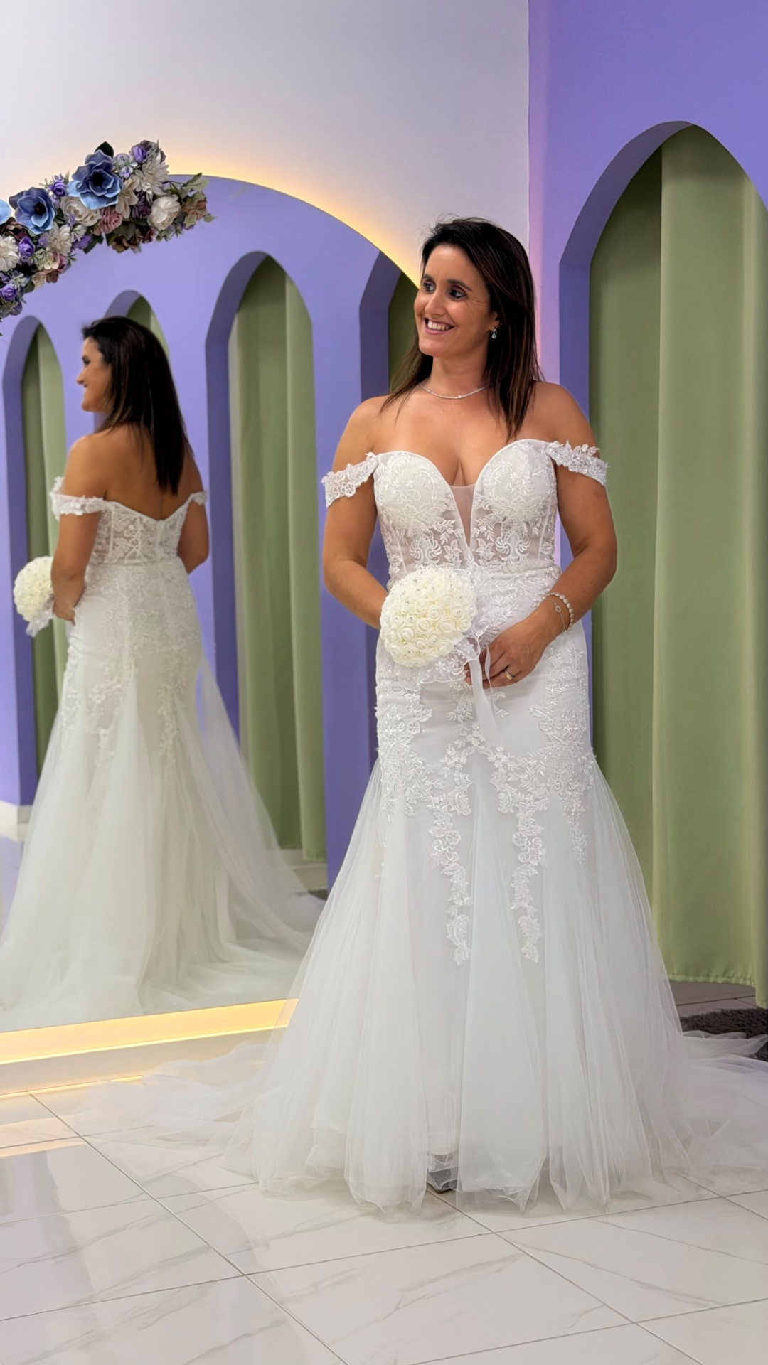 Vestido Wedding Ilusion Mulher a usar vestido de noiva branco com renda e tule e um bouquet de flores brancas.