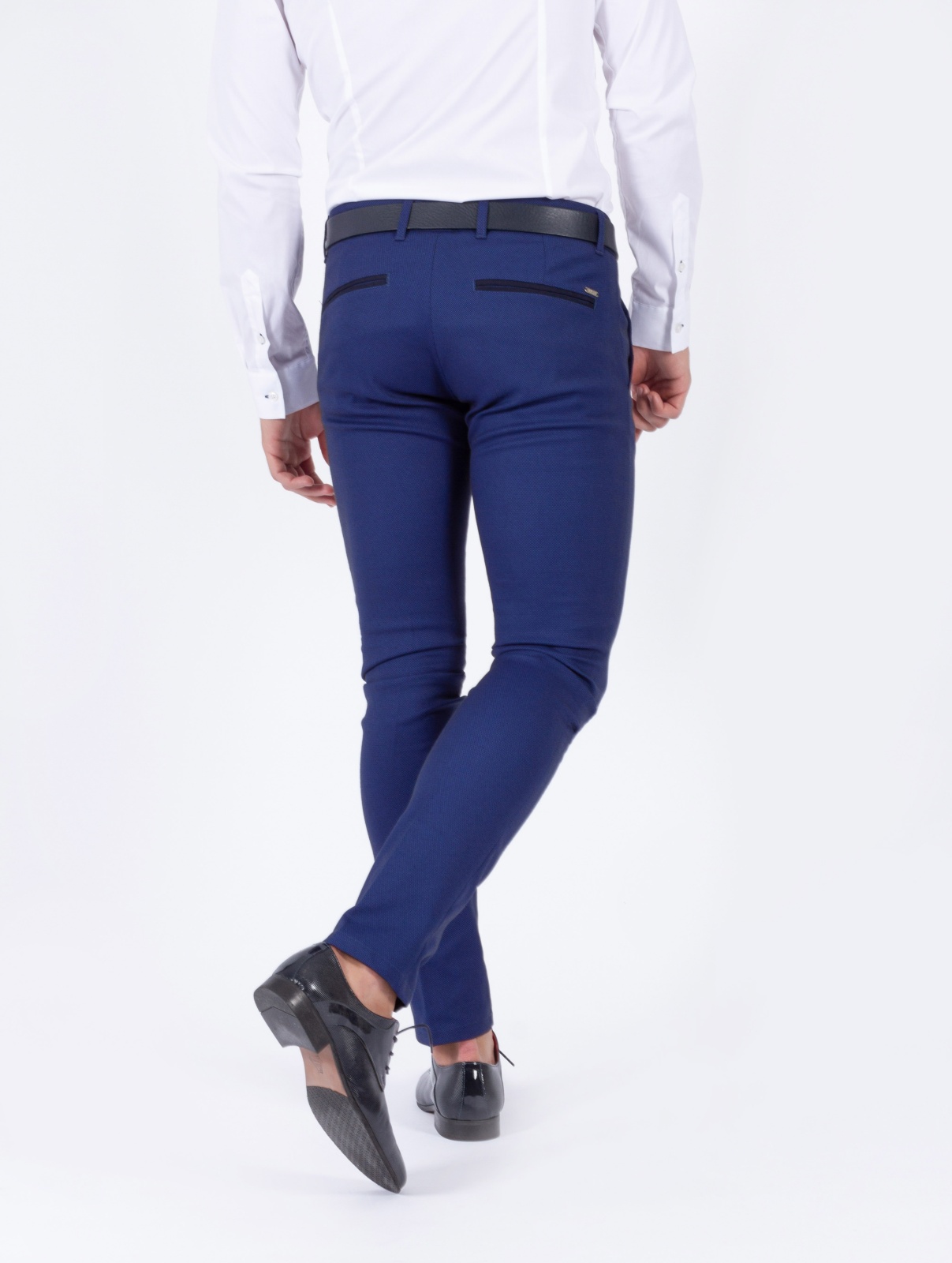 CALÇA SMK BLUE REFLECTION Calças azuis justas de homem com cinto preto e sapatos pretos, vista traseira