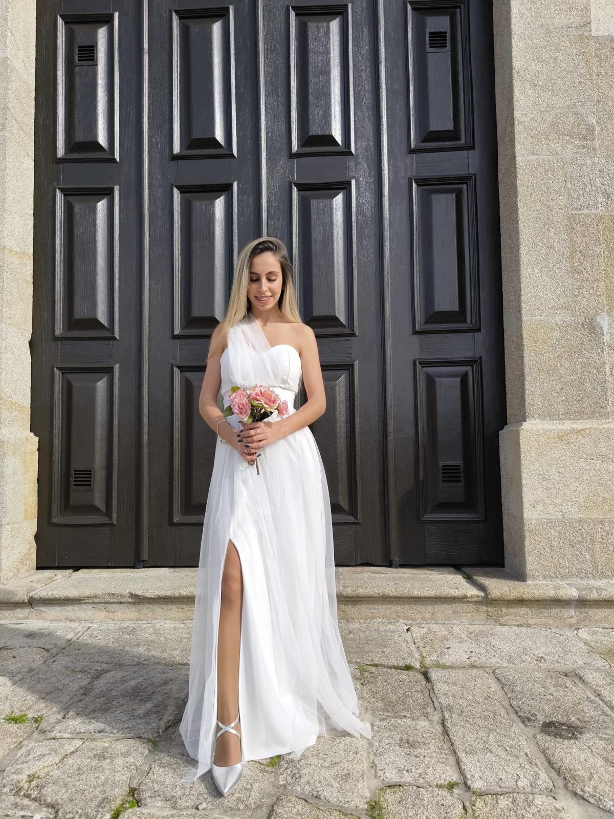 Elegância Minimalista - Vestido Noiva Mulher com vestido branco longo e bouquet em frente a porta preta