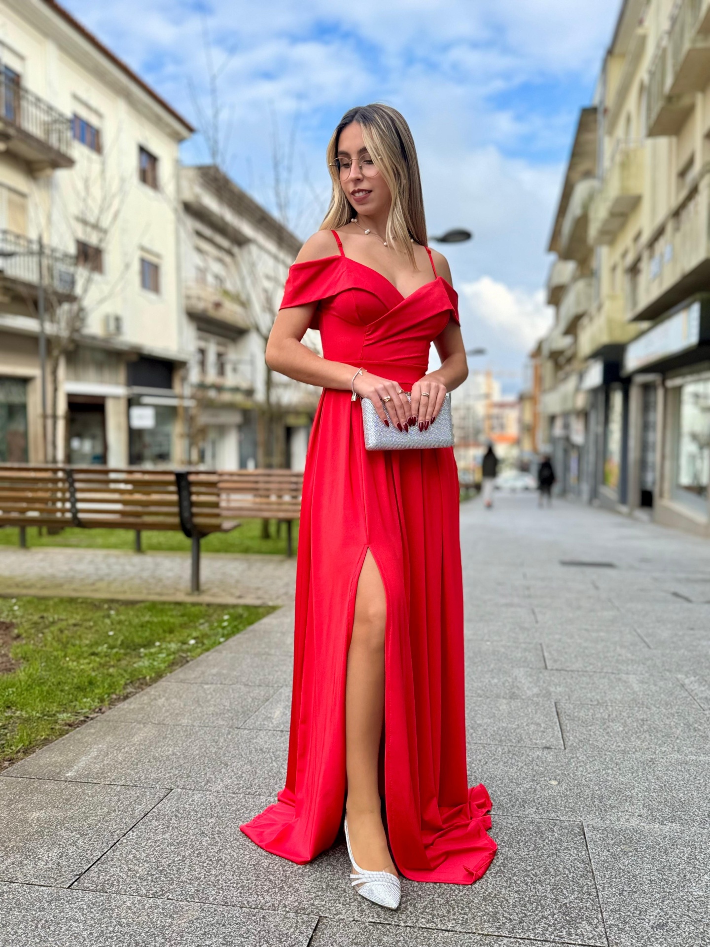 Vestido Eleganza Mulher com vestido longo vermelho e clutch prateada numa rua urbana
