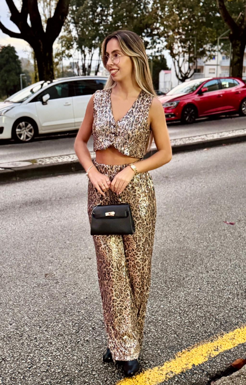 Conjunto Snake Lantejoulas Mulher com conjunto animal print dourado segurando mala preta na rua