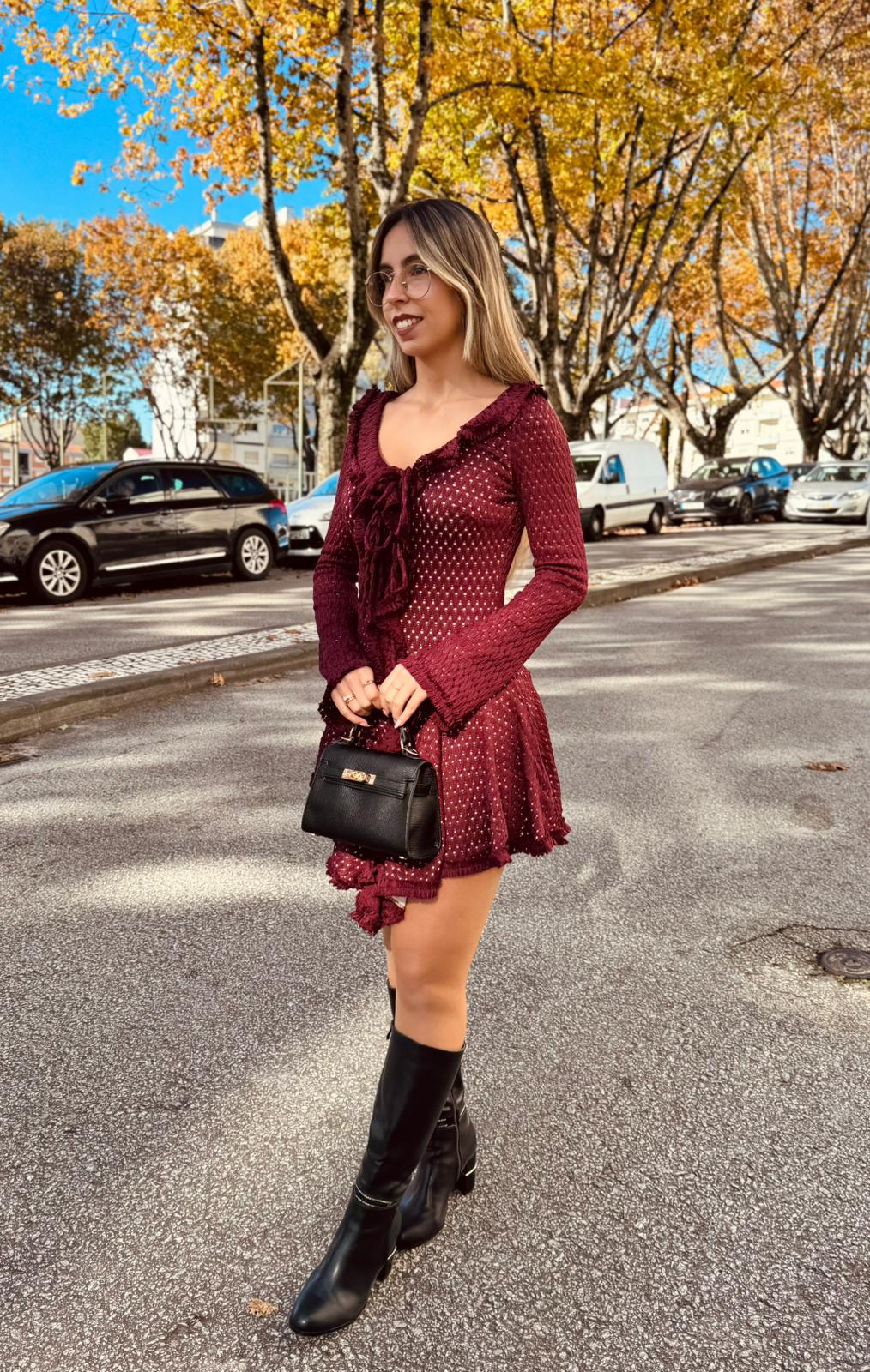 Vestido Tricot Charm Mulher com vestido bordô de malha e bota preta em rua com árvores outonais