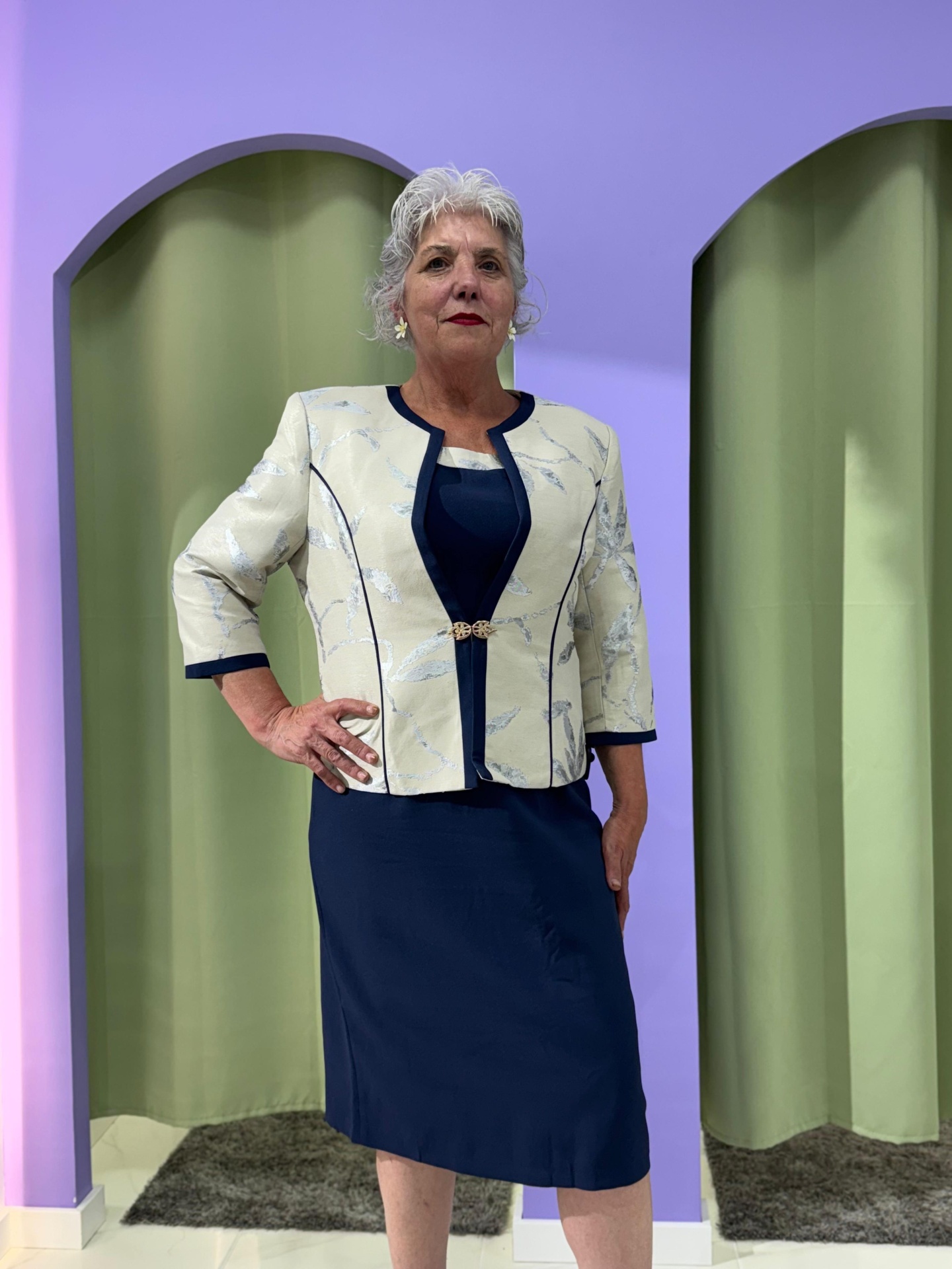 Conj. Casaco + Vestido Serena Conjunto feminino azul e bege com casaco floral num cenário com arcadas lilás e cortinas verdes