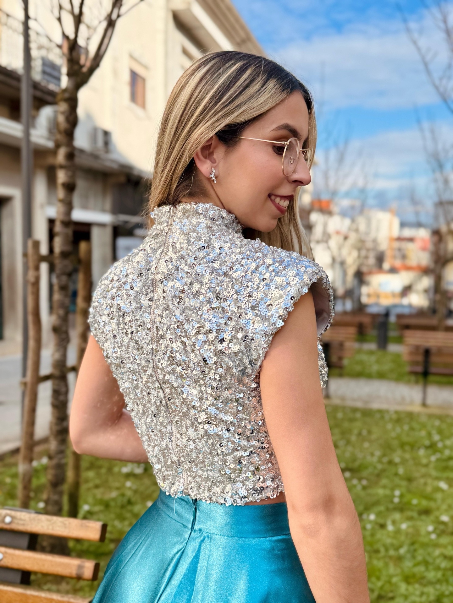 Conjunto Lumiar Blusa cropped prateada com lantejoulas e saia azul metálica em ambiente urbano