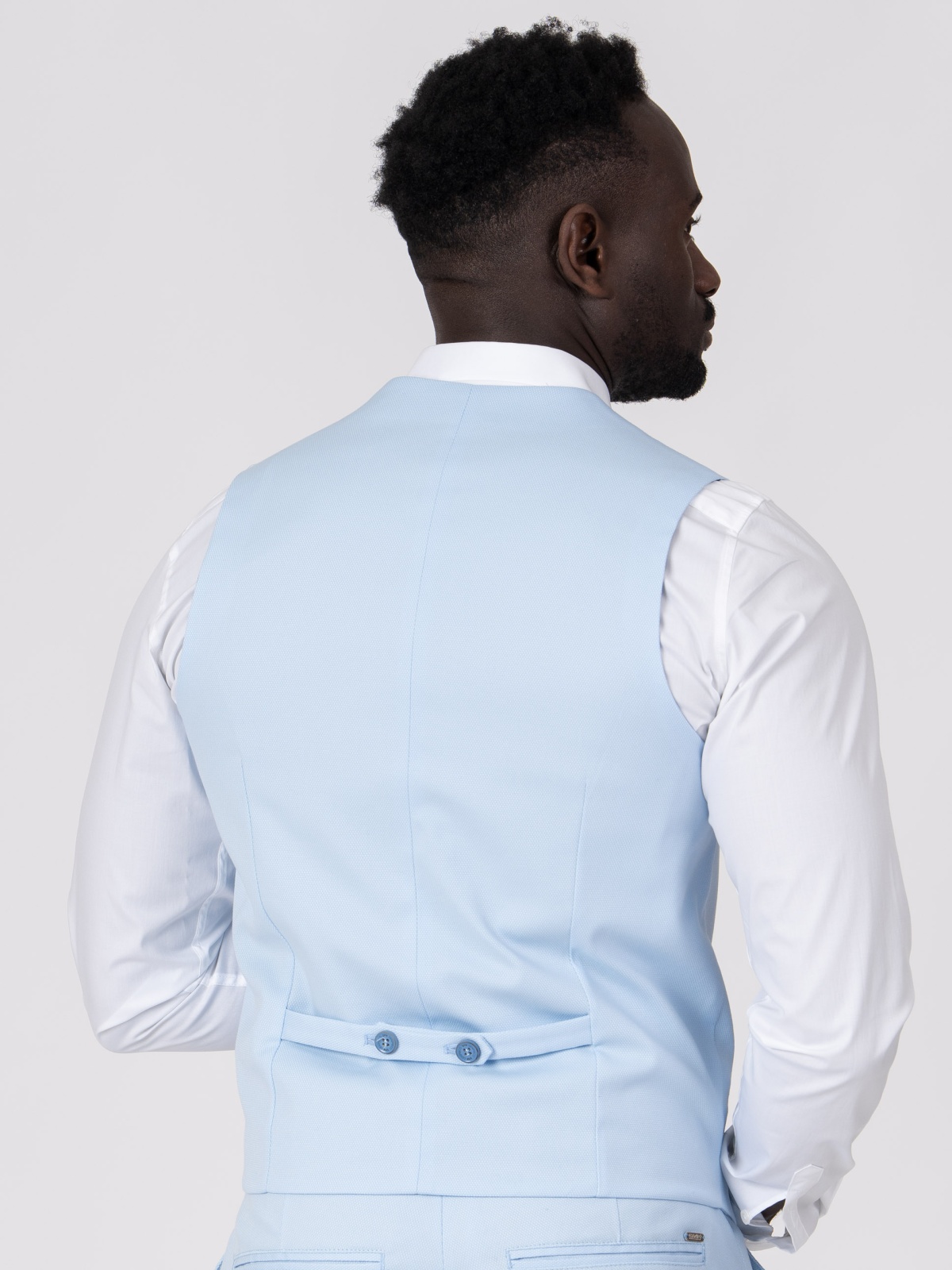 Colete SMK Azul Claro Homem de costas com colete azul claro e camisa branca