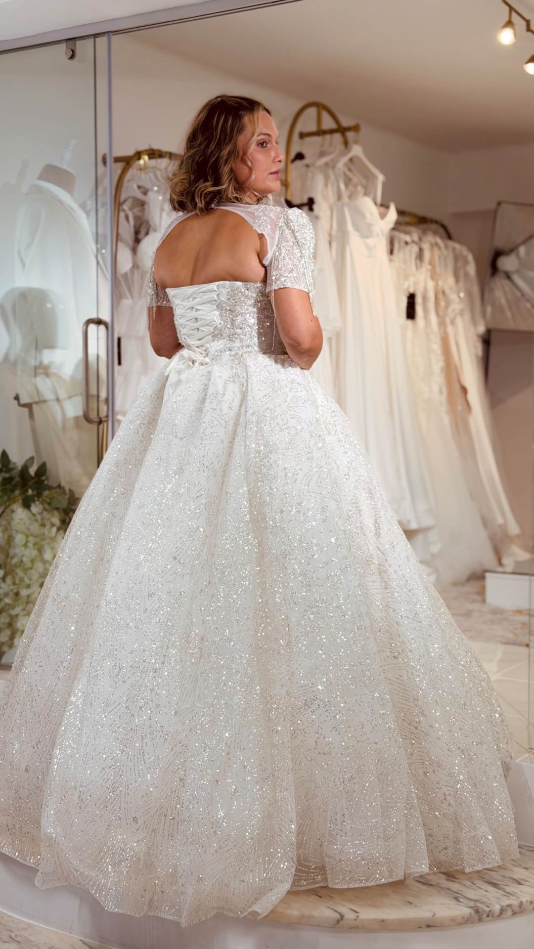 Vestido Wedding Aurora Vestido de noiva branco com brilhos e mangas curtas transparentes num provador