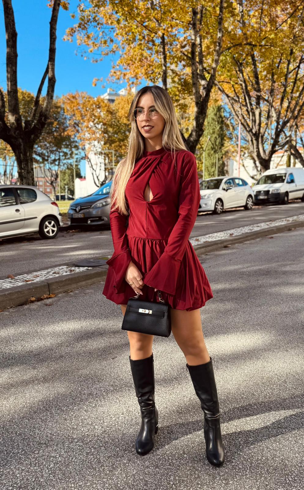 Vestido Licra Infinity Mulher com vestido vermelho curto e botas pretas em rua com árvores e carros ao fundo