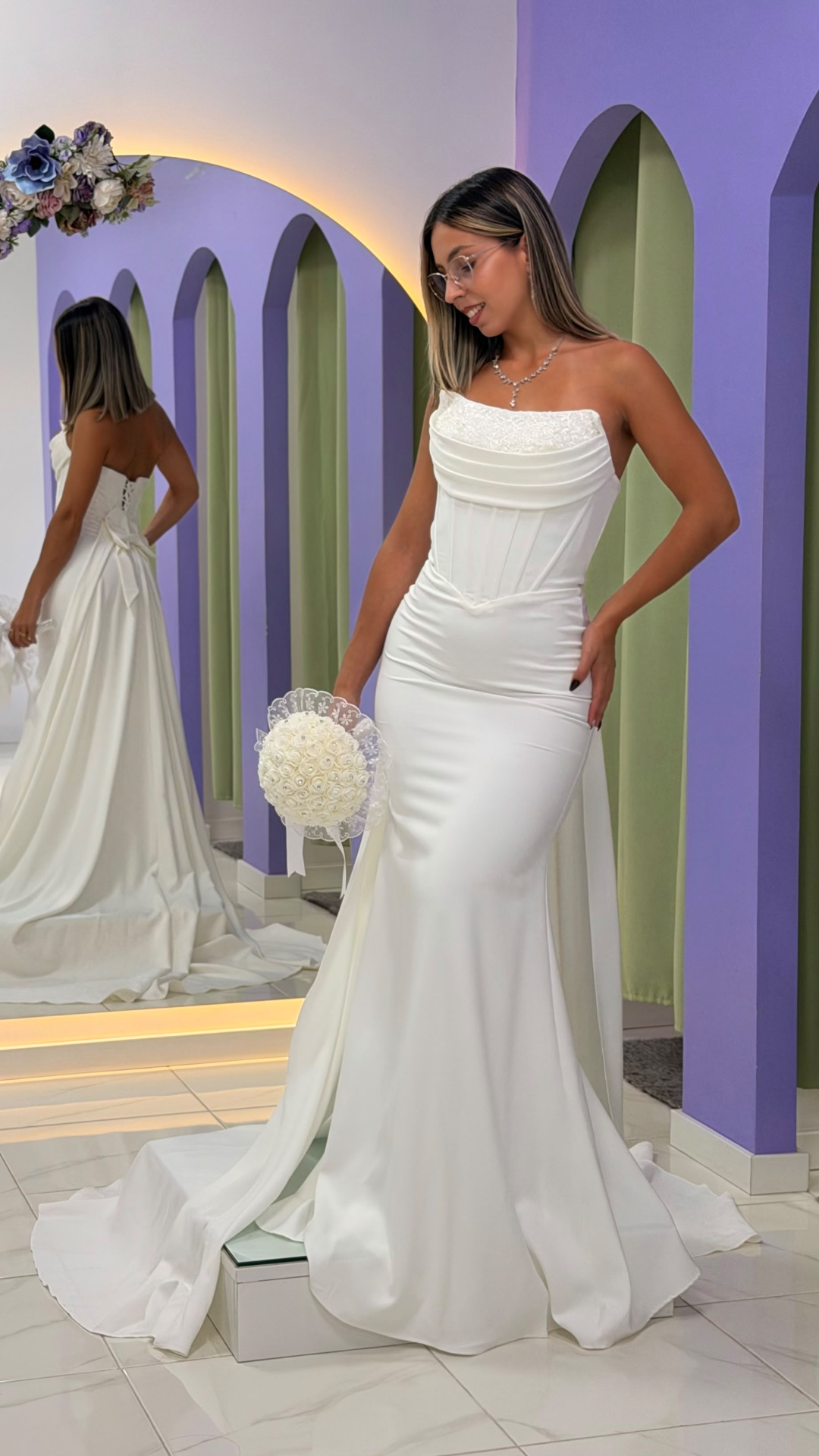 Vestido Éden Noiva Vestido de noiva branco com corpete justo e saia longa em ambiente com paredes lilás