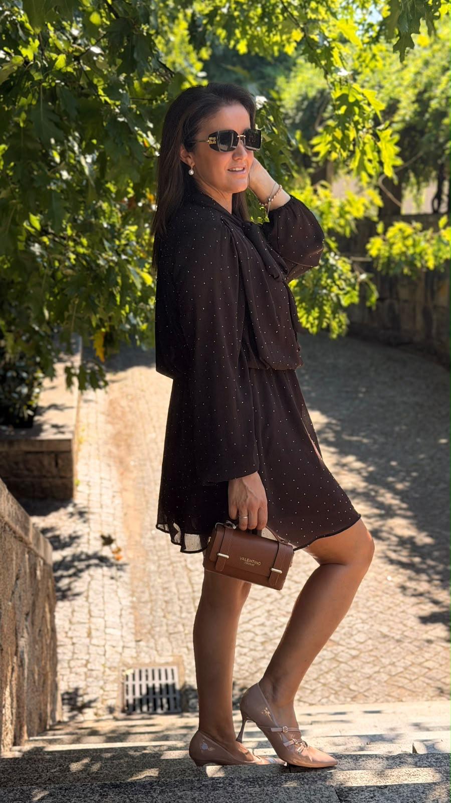 Vestido R&L Castanho Mulher com vestido preto de pontos brancos e mala Valentino castanha ao ar livre