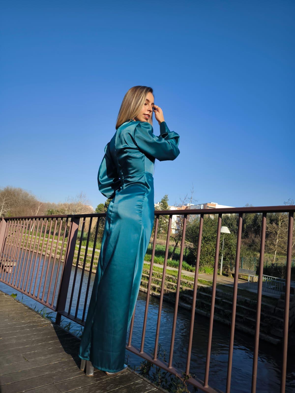 Vestido comprido c/ manga em cetim Mulher com roupa azul de cetim junto a rio numa ponte