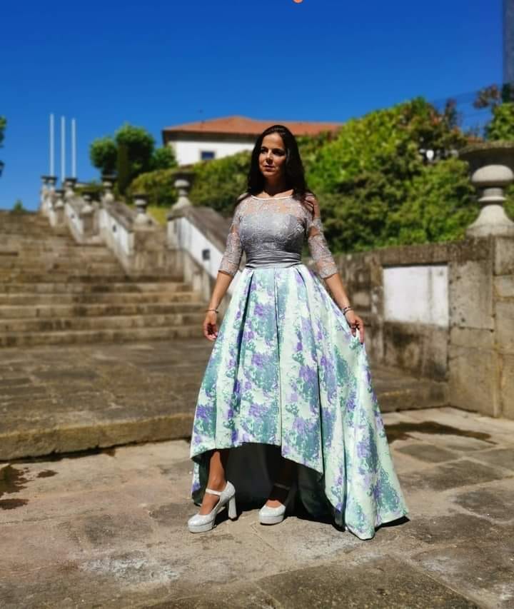 Vestido Mizuky Vestido de festa com corpete de renda cinzenta e saia floral assimétrica, sapatos brancos, ao ar livre com escadas e plantas