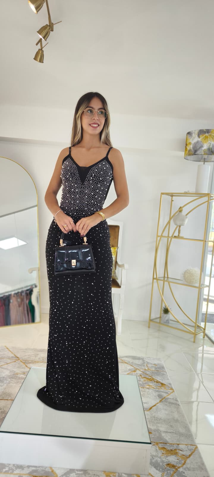 Vestido Tendy c/Pérolas Modelo feminina com vestido longo preto com brilhos e mala preta