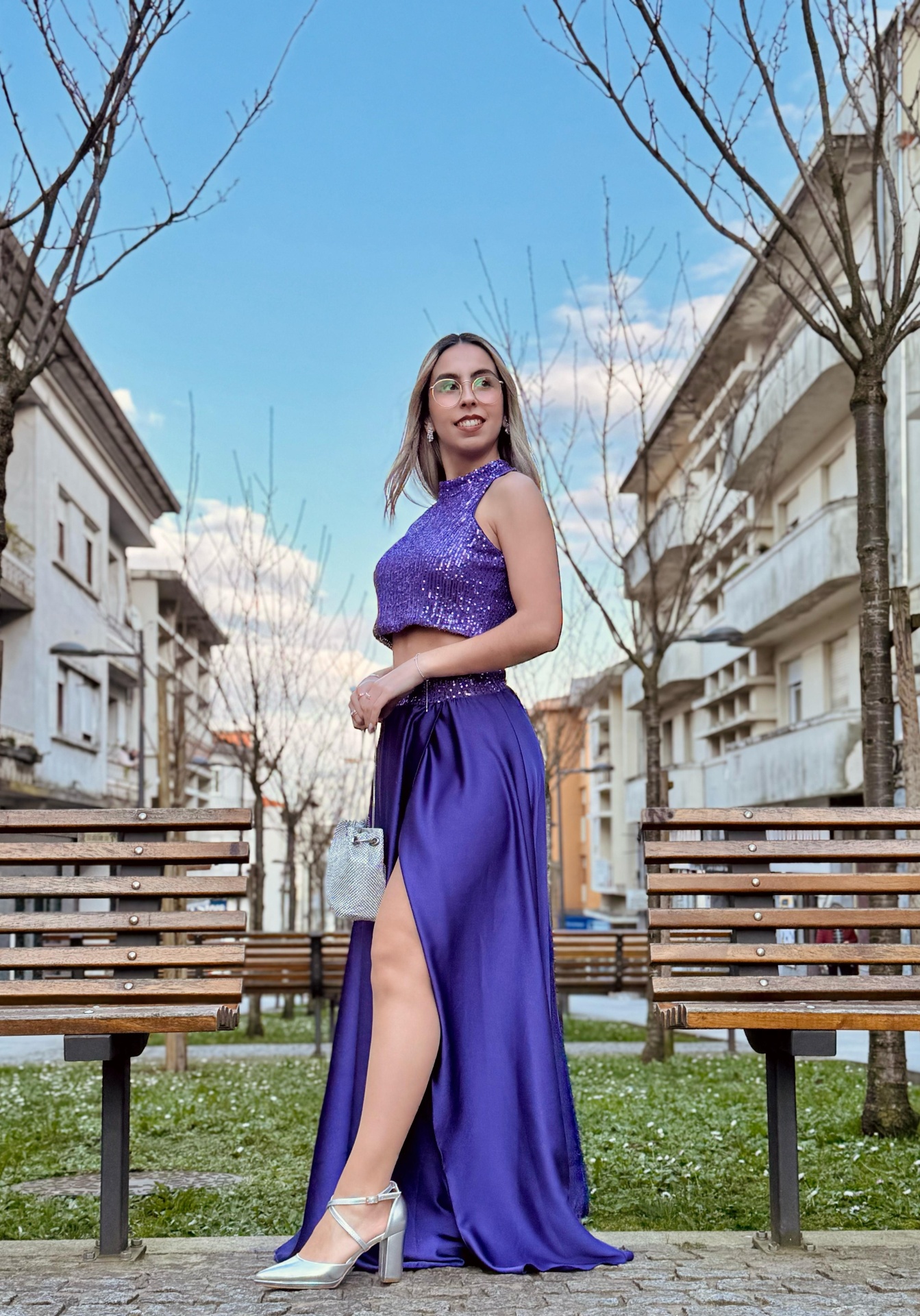 Conjunto Irina Veste longa roxa com racha lateral e sapatos prateados em cenário urbano