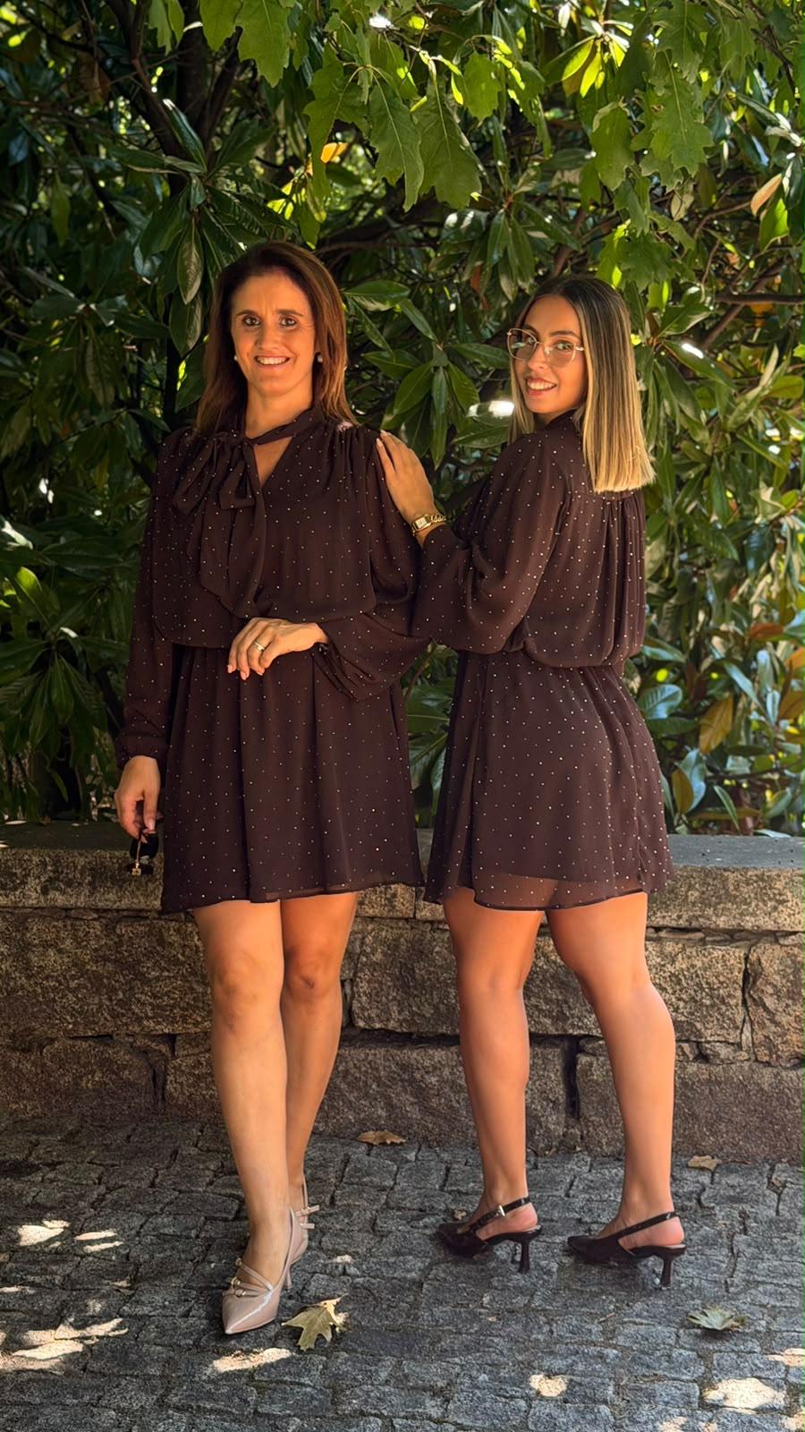 Vestido R&L Castanho Duas mulheres com vestidos castanhos curtos de pontos pequenos, sapatos de salto e árvores ao fundo