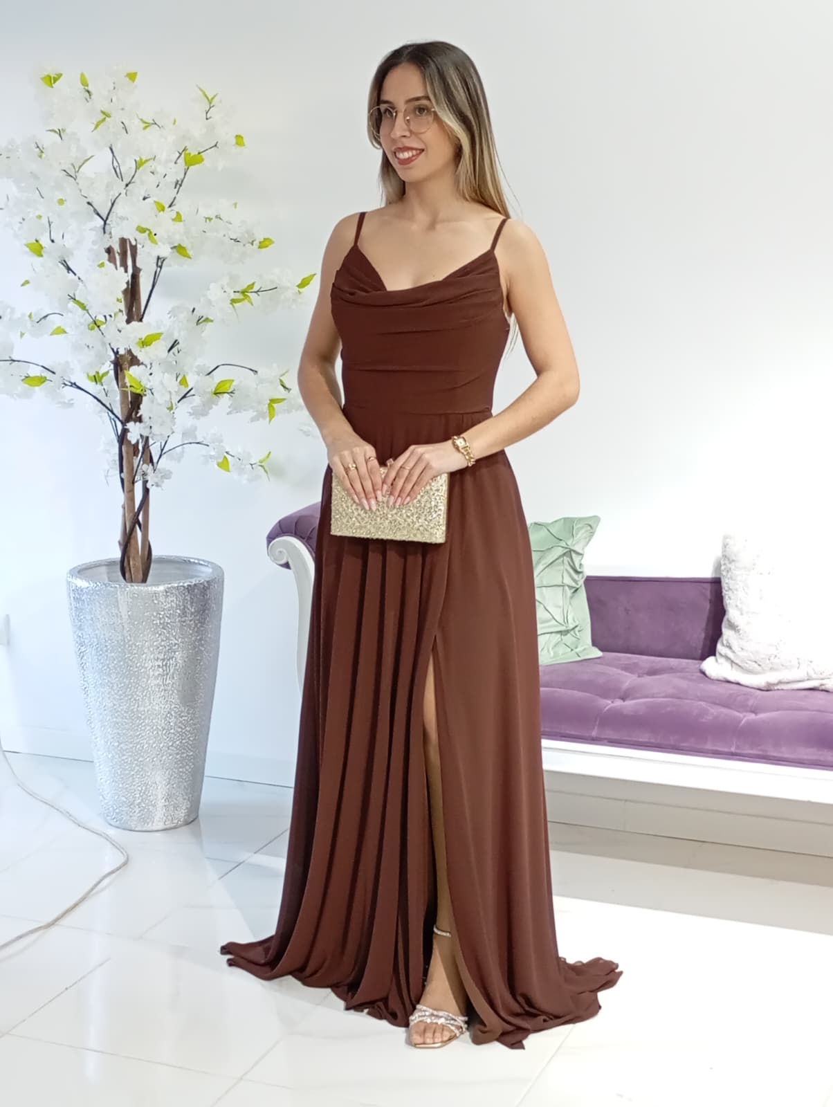 Vestido Charm's Nuria Castanho Mulher a usar vestido castanho longo com alças finas e a segurar mala dourada brilhante