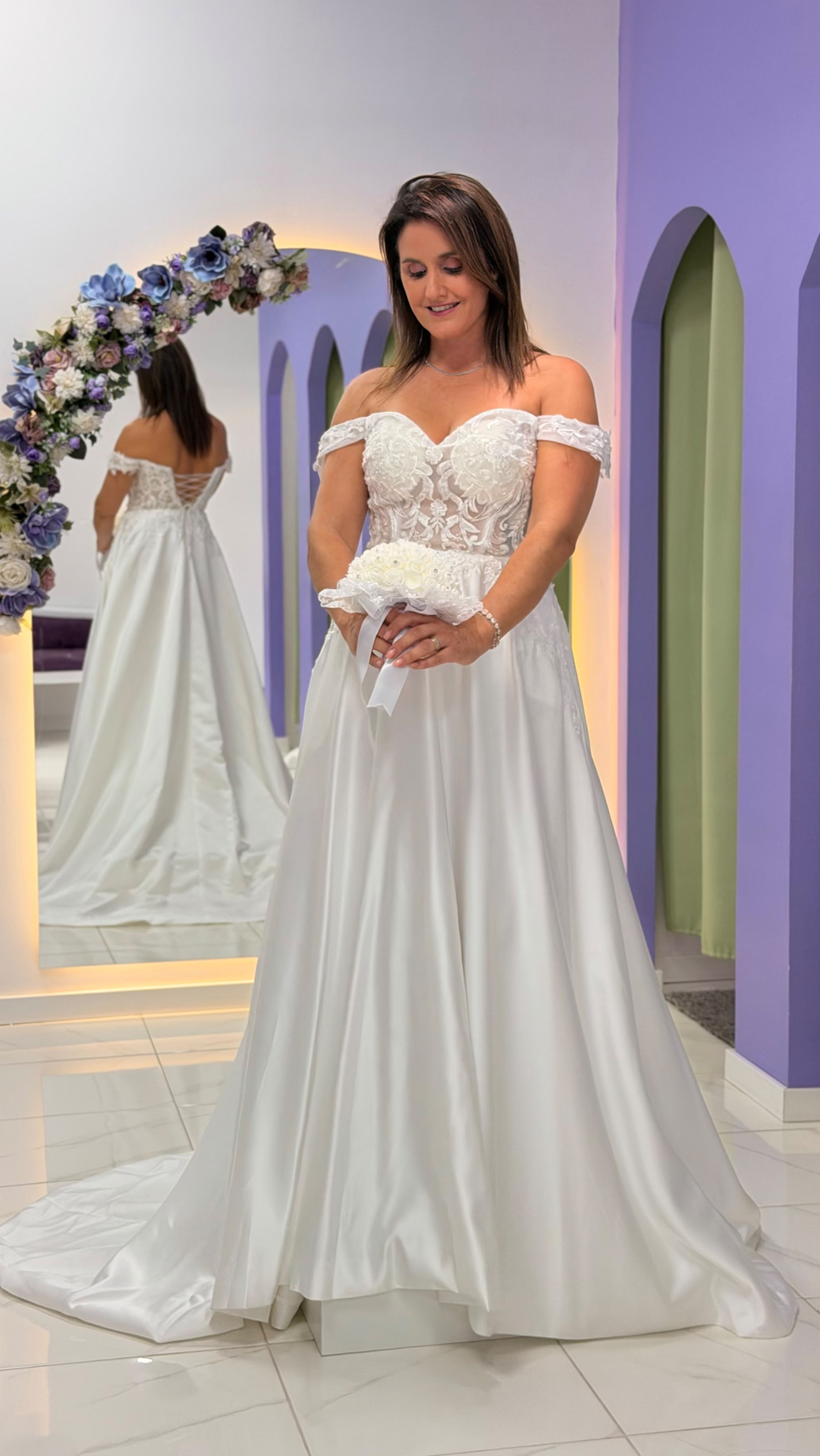 Vestido Amour Glamour Vestido de noiva branco com corpete de renda e saia ampla em ambiente com espelho decorado