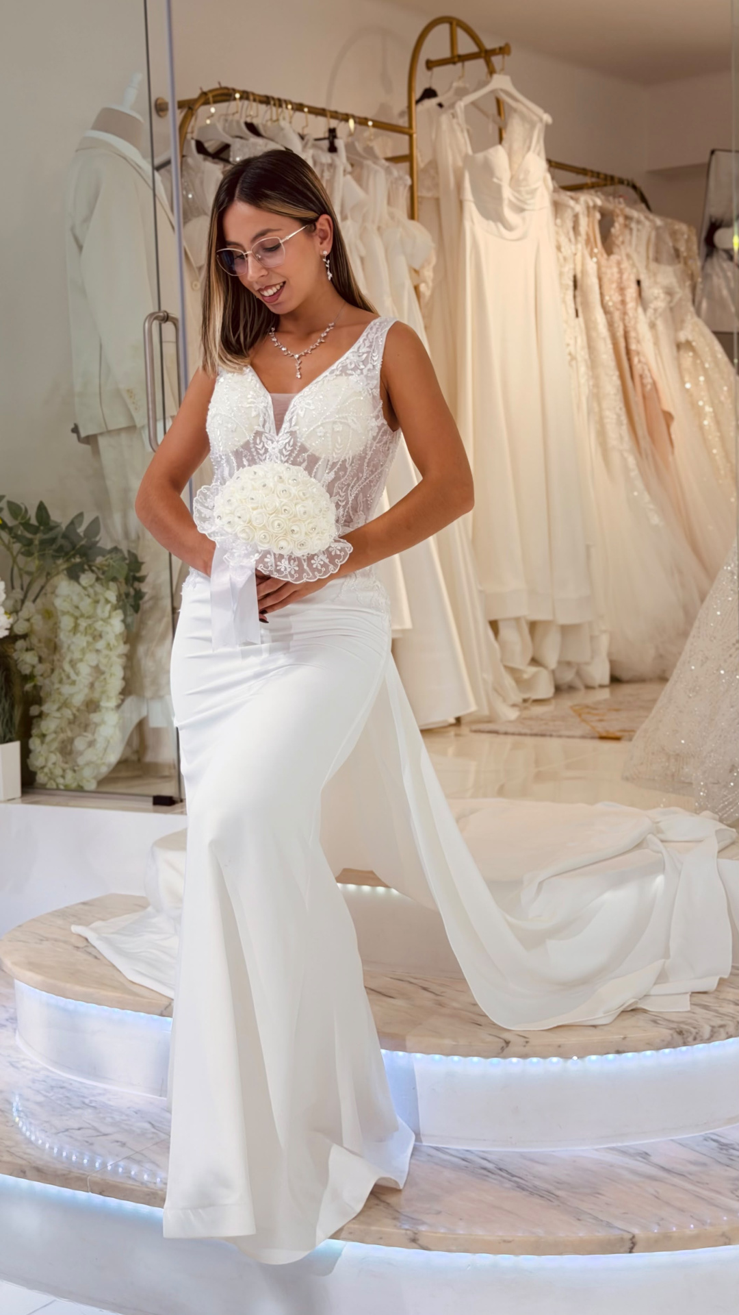 Vestido Denielle Noiva Mulher em vestido de noiva branco com bouquet branco em loja de vestidos