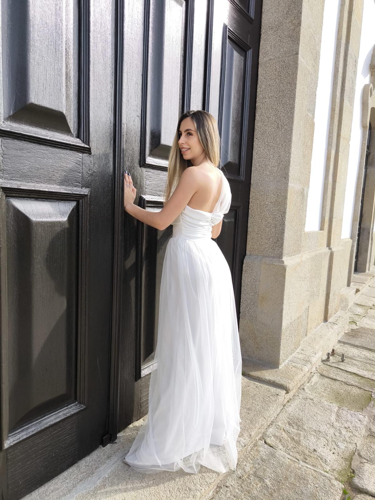 Elegância Minimalista - Vestido Noiva Mulher com vestido longo branco junto a porta preta de madeira