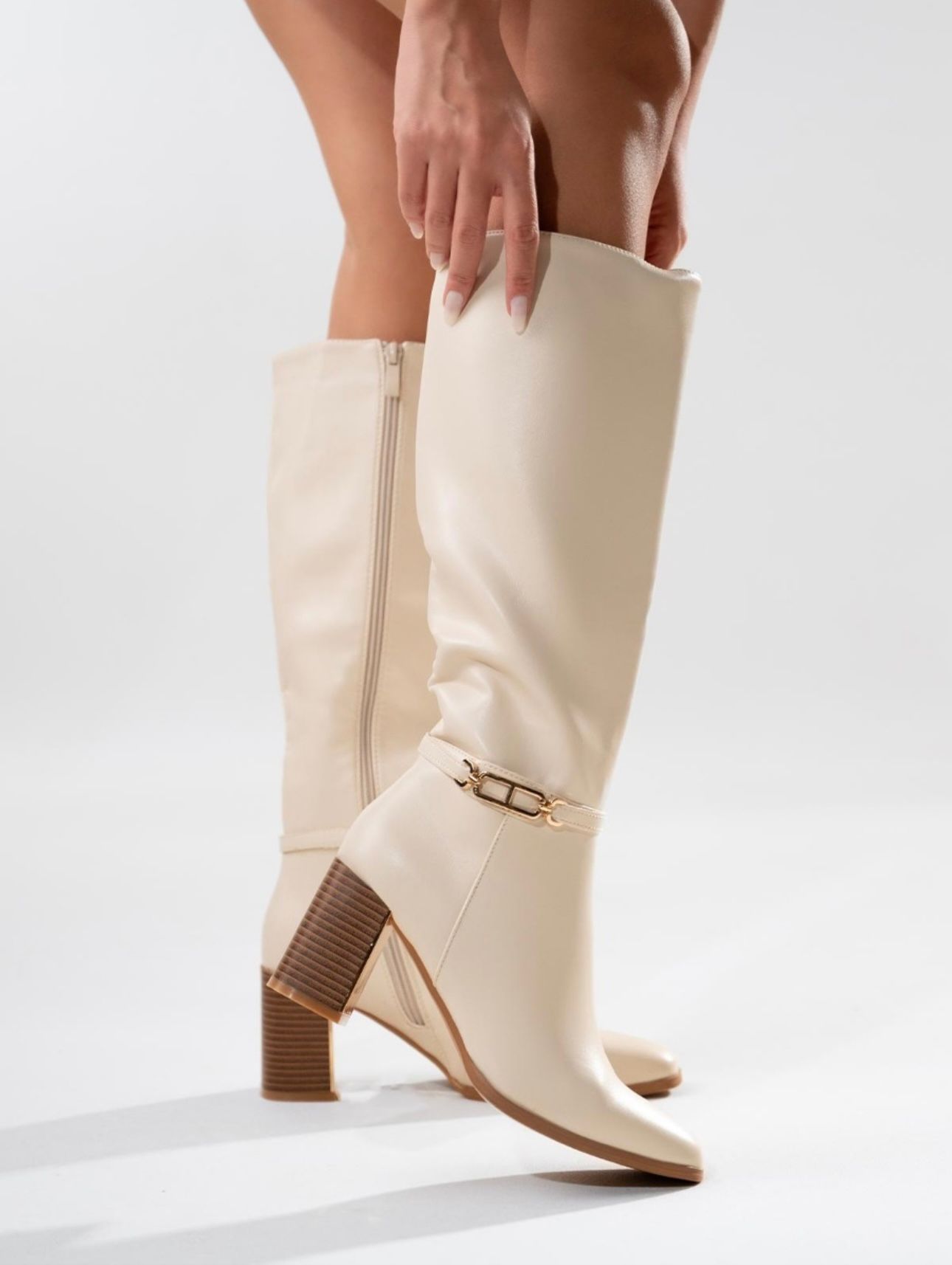 Bota Cano Alto C/ Fivela Botas femininas bege claro com salto médio largo e detalhe dourado.