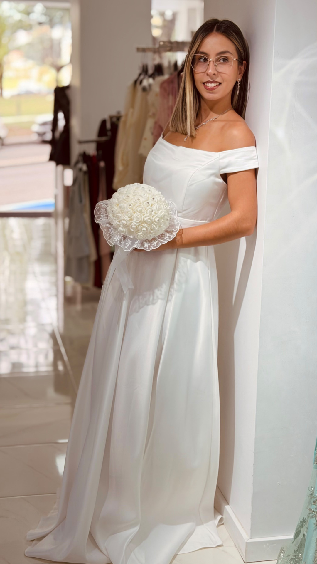 Vestido Santa Noiva Mulher com vestido de noiva branco e bouquet de flores brancas, em ambiente interno