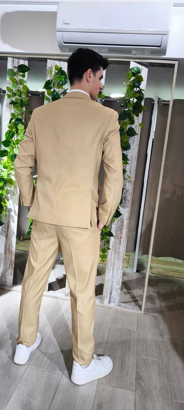 Fato Gilgavin Bege Ponteado Homem de costas com fato bege e sapatos brancos em ambiente interior com espelho e plantas verdes