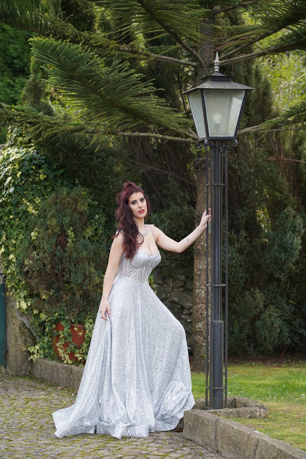 Vestido Princess Glow Vestido longo prateado com brilho usado por mulher junto a candeeiro ao ar livre