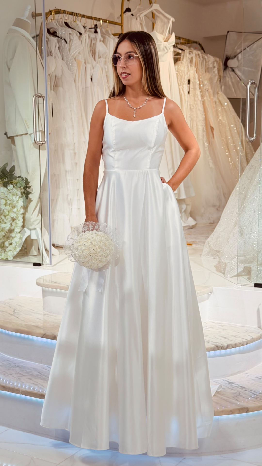 Vestido Helene Noiva Vestido de noiva branco acetinado com alças finas e ramo branco em loja