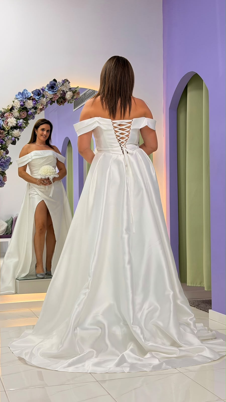 Vestido Aurora Noiva Vestido de noiva branco em tecido acetinado com decote ombro a ombro e costas entrelaçadas, com saia longa e racha frontal