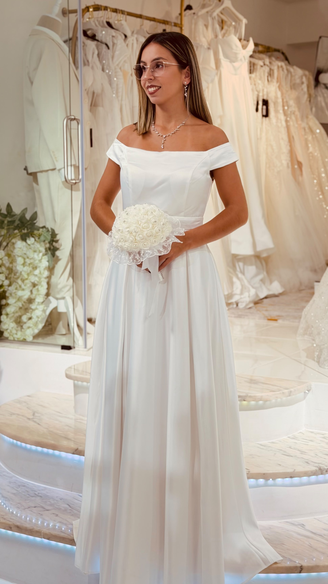 Vestido Santa Noiva Mulher de vestido de noiva branco com bouquet branco em showroom