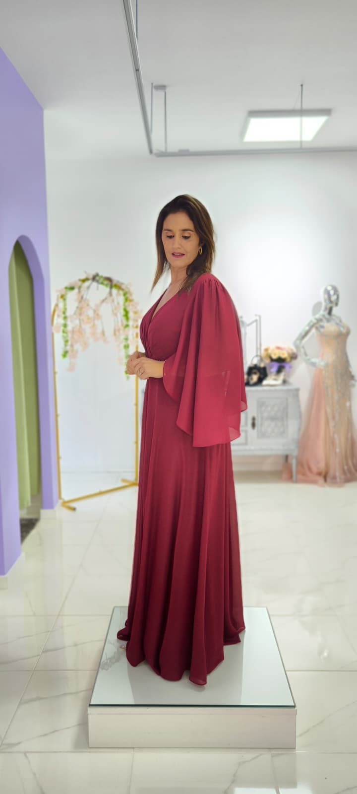 Vestido Leonor c/ Capa Plus Size Vestido longo vinho com mangas amplas e decote em V num espaço interior moderno