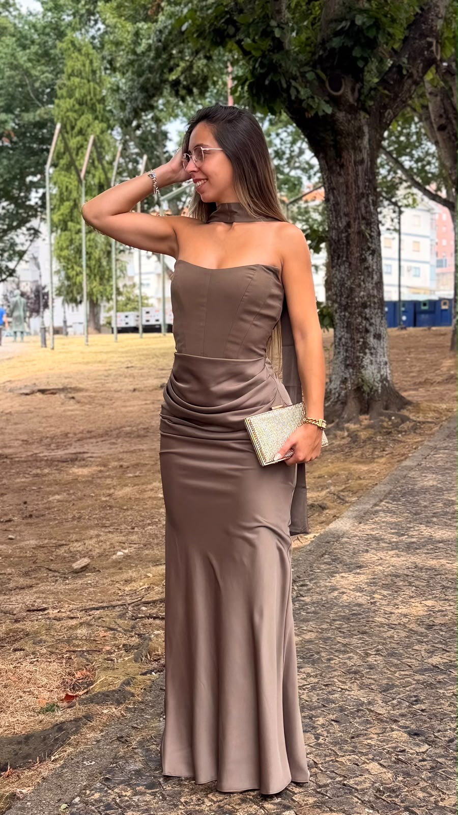 Vestido Romana Vestido longo castanho brilhante com decote tomara que caia e carteira dourada ao ar livre