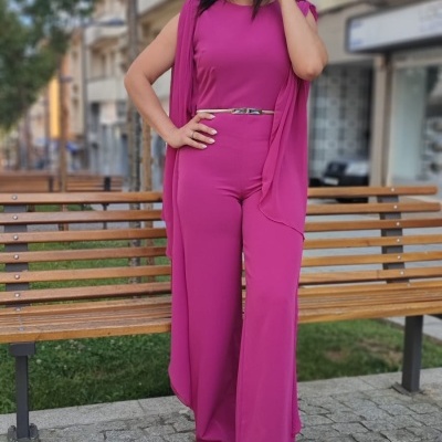 Macacão rosa fúcsia com calças largas e cinta decorativa, mulher em ambiente urbano