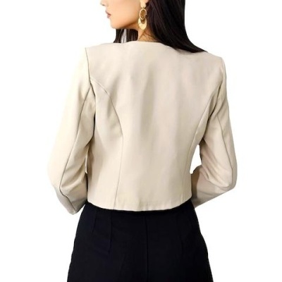 Casaco curto bege feminino visto por trás, com calças pretas e fundo branco