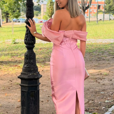 Mulher num vestido rosa cetim comprido com ombros descobertos e sandálias brancas