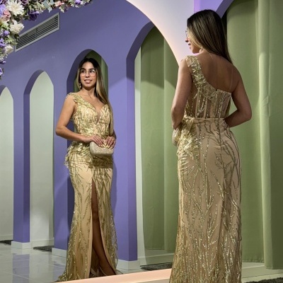 Mulher com vestido dourado longo em frente a espelho com decoração floral